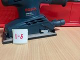 La ponceuse orbitale Bosch est posée sur une table, à côté d'une boîte rouge