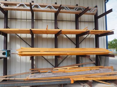 Plusieurs morceaux de bois sont empilés les uns sur les autres devant un bâtiment.