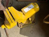 un étau jaune posé par terre à côté d'une boîte