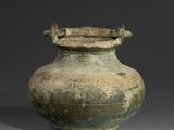un grand vase vert posé sur une surface grise
