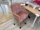 a pink chair sitting in front of a desk with a phone on it