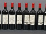 six bottles of red wine are lined up on a table