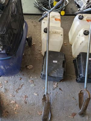 deux tondeuses à gazon, un ventilateur et une poubelle posés par terre