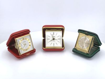 three different colored clocks sitting on top of a white table