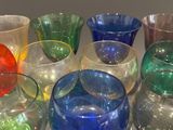many different colored glasses sitting in a row on a table