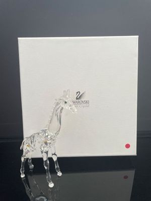 une figurine de girafe en verre posée sur une table