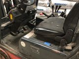 a forklift with a seat and steering is parked in a warehouse