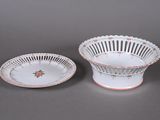 two white and red dishes with floral designs on them on a gray surface