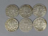 four silver coins with a coat of arms and a crown on them