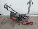 an image of a lawn mower parked in front of a garage