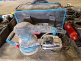 une photo d'une boîte à outils contenant une ponceuse et d'autres outils