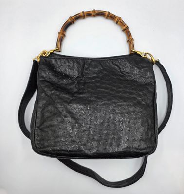 un sac en cuir noir avec des anses en bambou sur fond blanc