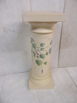un vase blanc orné de feuilles vertes, posé sur une table