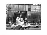 black and white photograph of a person holding up a peace sign in front of a trump tower