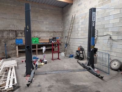 une photo d'un garage avec un chariot élévateur au milieu de la pièce