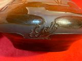 un vase marron orné d'un motif noir sur fond rouge