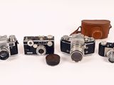 several old cameras are lined up in a row on a white surface