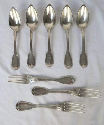 six cuillères et six fourchettes en argent sont disposées sur une nappe blanche