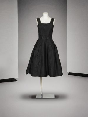 une robe noire posée sur un mannequin devant un mur blanc