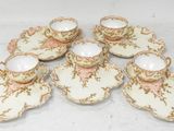 six tasses et soucoupes sont posées sur une surface blanche