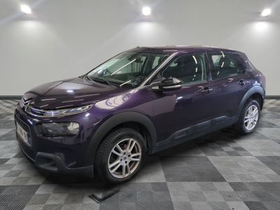 La voiture violette est garée dans le garage, sur un sol à damier.