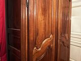 a large wooden armoire in a room with a red curtain
