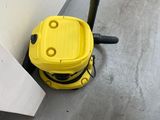 un aspirateur jaune posé par terre près d'un mur