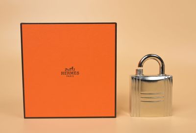 une boîte orange avec un cadenas argenté à côté, posée sur une surface beige