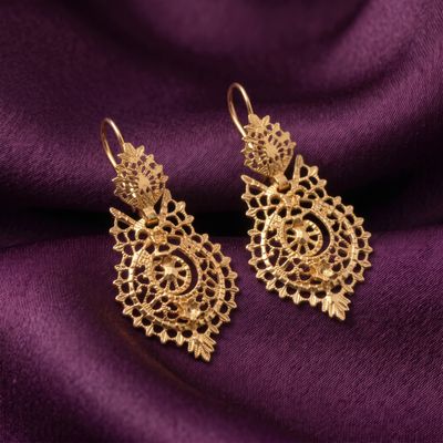 une paire de boucles d'oreilles en or posées sur un tissu violet