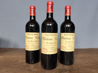 three bottles of red wine sitting on top of a wooden table