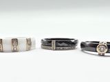 three black and white rings with diamonds on them on a white surface