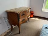 une commode dans un coin d'une pièce où se trouve une fenêtre