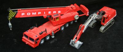 un camion jouet rouge et une grue rouge sur fond noir