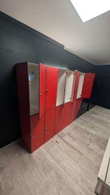 a row of red lockers in a room with a skylight