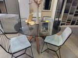 a glass table with chairs and a vase on top of it