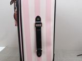 a pink and white striped suitcase sitting on the floor