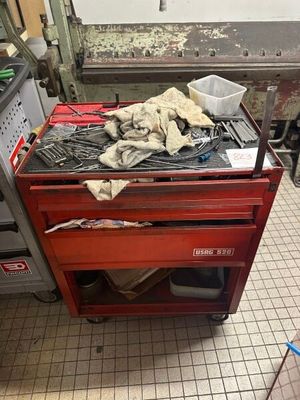 une boîte à outils rouge remplie d'outils, posée sur un sol carrelé