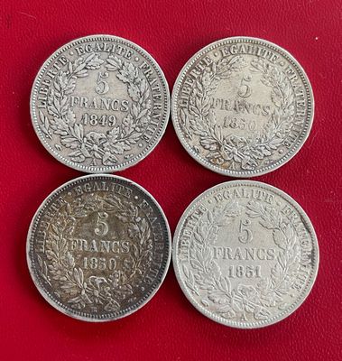 trois pièces d'argent, dont l'une a la même taille que les autres, se trouvent sur une surface rouge