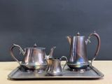 a silver tea set on a tray on a table