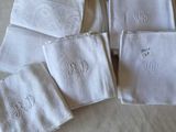 quatre serviettes blanches ornées de monogrammes brodés, posées sur un lit