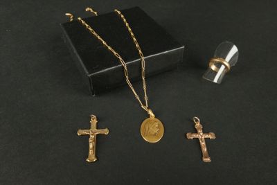 trois croix en or et un pendentif en forme de croix sur un fond noir