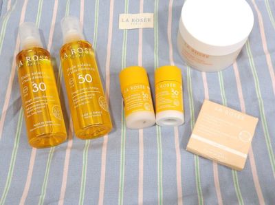 un flacon de crème solaire, un pot de crème et un pot de crème posés sur un lit