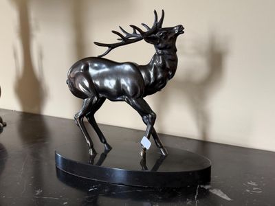 une statue de cerf posée sur une table, à côté d'une lampe