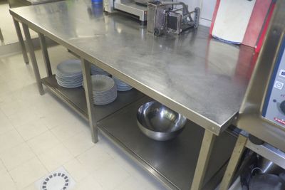 une grande table en acier inoxydable sur laquelle est posé un saladier