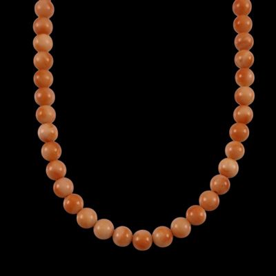 an orange jade bead necklace on a black background