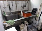 une cuisine équipée d'un évier et de nombreux ustensiles accrochés au mur