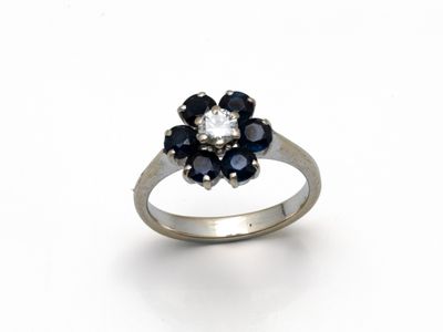 une image représentant une bague ornée d'une fleur en diamants et saphirs sur fond blanc