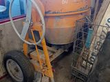 une bétonnière garée dans un garage, à côté d'un tas de pneus