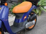 a blue scooter with an orange seat parked on the side of the street