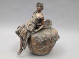 statue of a woman sitting on top of a vase with a dog